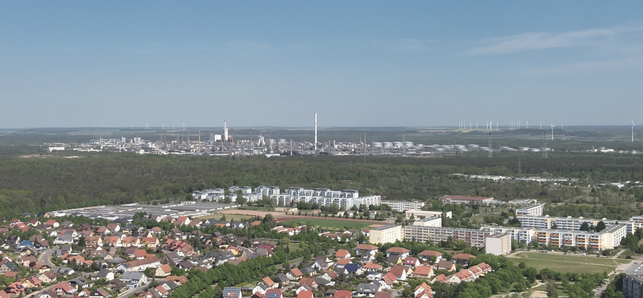 Luftaufnahme von Schwedt. Im Vordergrund Wohngebiete der Stadt, im Hintergrund erstreckt sich der weitläufige Industriekomplex der Raffinerie. 