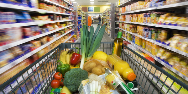 Voller Einkaufskorb zwischen den Regalen im Supermarkt
